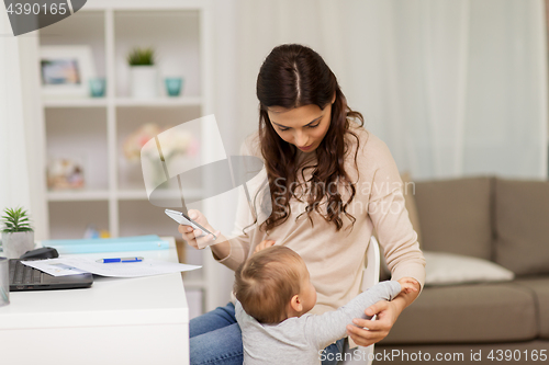 Image of baby boy disturbing mother working at home