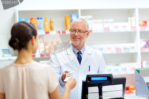 Image of customer giving money to pharmacist at drugstore