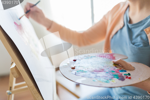 Image of artist with palette and brush painting at studio