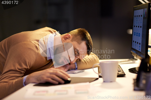 Image of tired man sleeping on table at night office