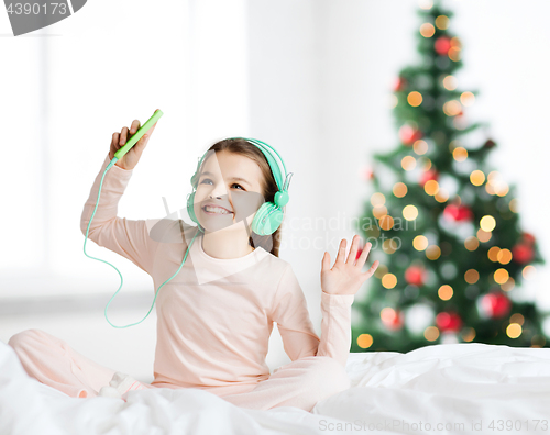 Image of girl with smartphone and headphones at christmas