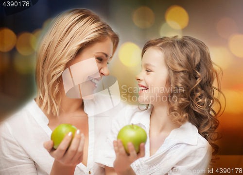 Image of happy mother and daughter with green apples