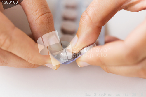 Image of woman hands opening pack of medicine pills