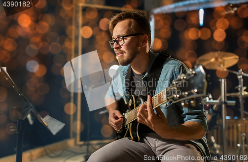 Image of man playing guitar at studio or concert 