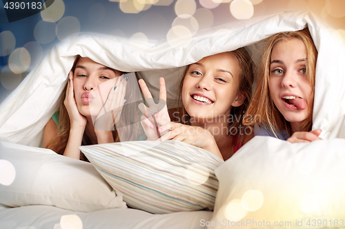 Image of happy young women in bed at home pajama party