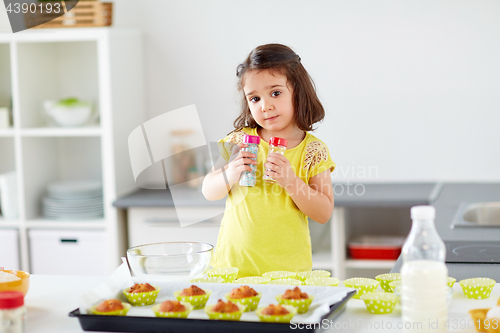 Image of little girl in chefs toque baking muffins at home