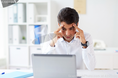 Image of stressed businessman with laptop at office