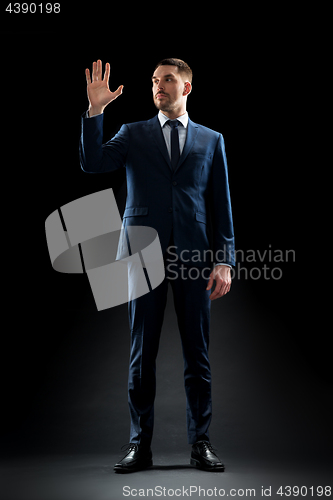 Image of businessman in suit touching something invisible