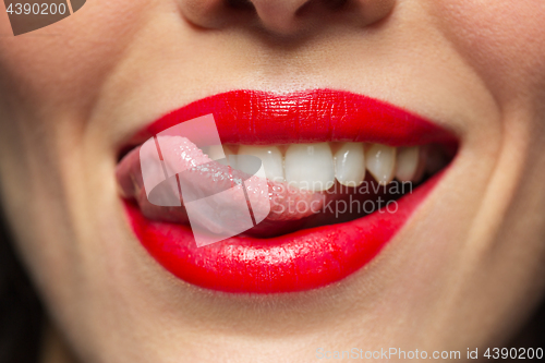 Image of close up of woman with red lipstick licking lips