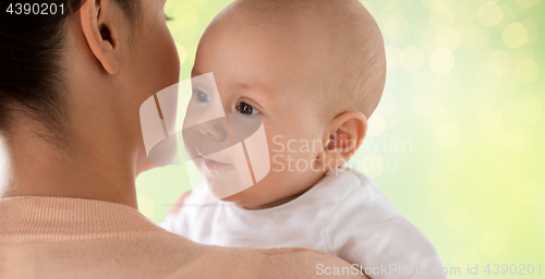 Image of close up of happy baby with mother over green