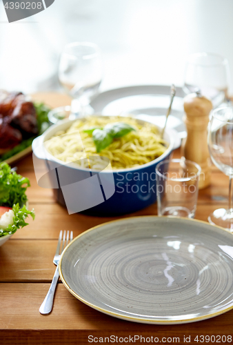 Image of empty plate and fork on wooden table with food