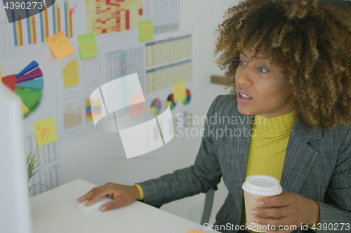 Image of Young worker having coffee while using computer