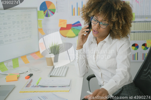 Image of Thoughtful woman in office talking on phone