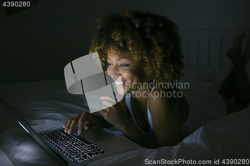 Image of Smiling woman chatting with laptop in dark