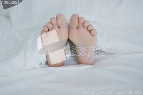 Image of Crop female feet under blanket