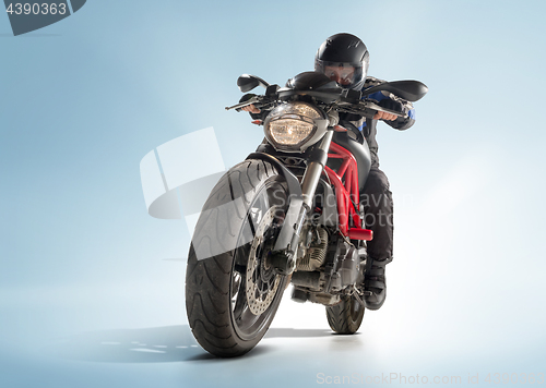 Image of Biker in black jacket and helmet sitting on his sportive bike on blue background