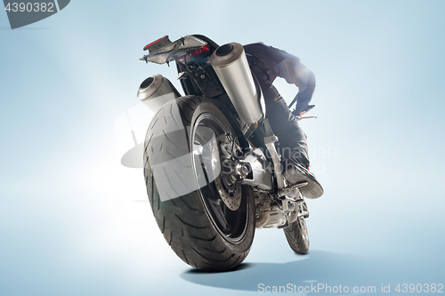 Image of Biker in black jacket and helmet sitting on his sportive bike on blue background