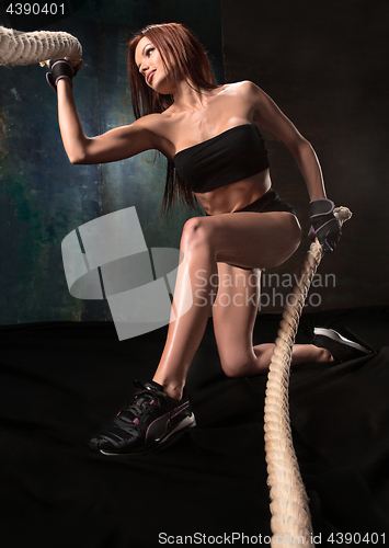 Image of The strong young woman pulling rope at a gym