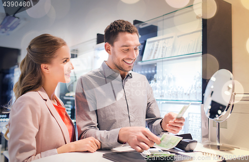 Image of happy couple paying for purchase in store