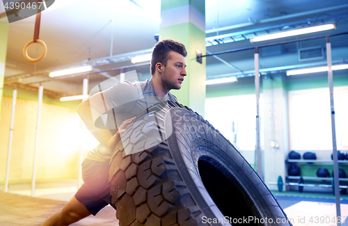 Image of man doing strongman tire flip training in gym