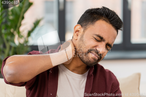 Image of unhappy man suffering from neck pain at home