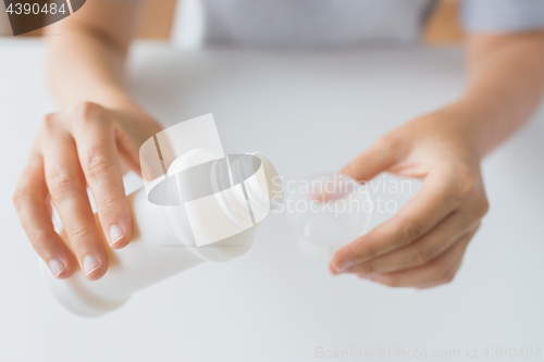 Image of woman pouring syrup from bottle to medicine cup