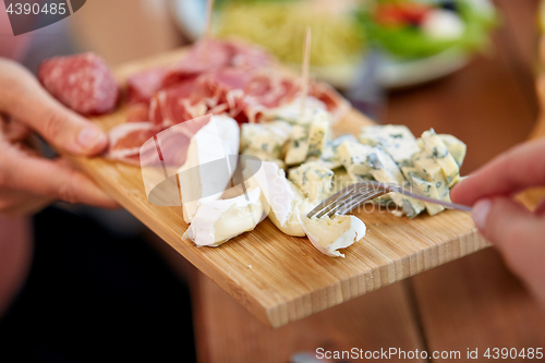 Image of hands with blue cheese and jamon or ham on board