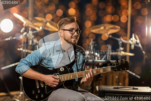 Image of musician playing guitar at studio over lights