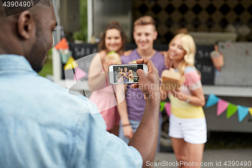 Image of man taking picture of friends eating at food truck