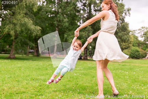 Image of happy mother playing with baby girl at summer park