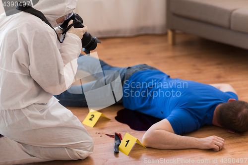 Image of criminalist photographing dead body at crime scene