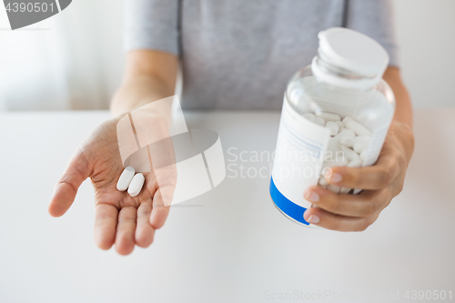 Image of close up of hands holding medicine pills and jar