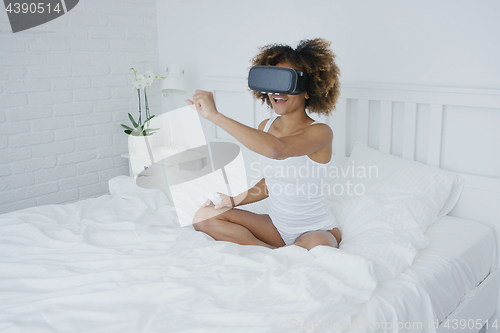 Image of Content woman in VR glasses on bed