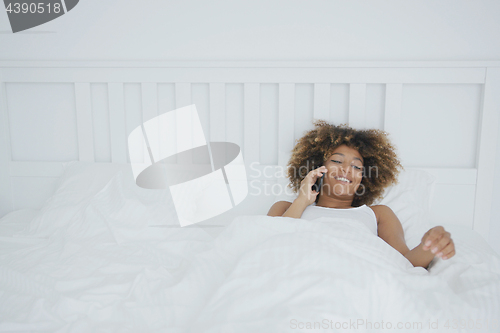 Image of Smiling woman in bed having phone call