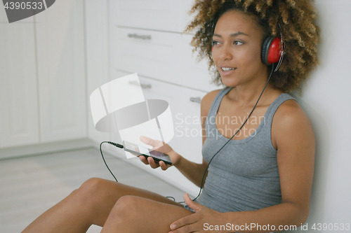 Image of Young woman with headphones in kitchen