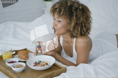Image of Dreaming woman having sweet meal in bed