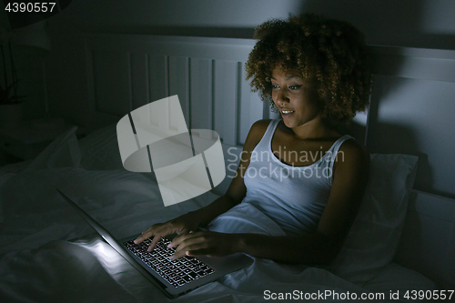 Image of Young woman using laptop in night