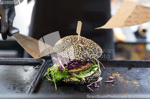 Image of Chef preparing burgers at grill plate on international urban street food festival.