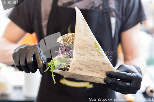 Image of Chef serving organic vegetarian fish burger at international urban street food festival.