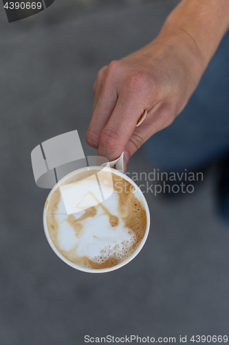 Image of Hand holding a cup of coffee to go.