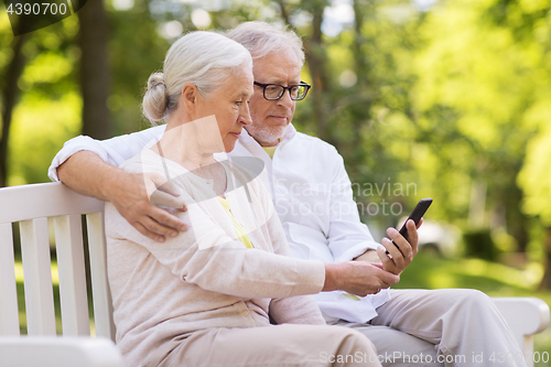 Image of happy senior couple with smartphone at park