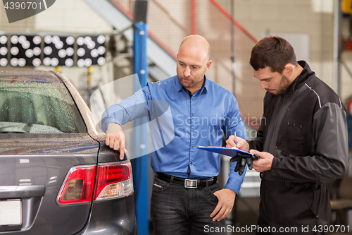 Image of mechanic and customer looking at car taillight