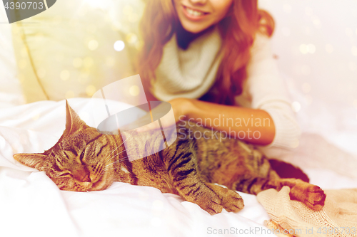 Image of happy young woman with cat lying in bed at home