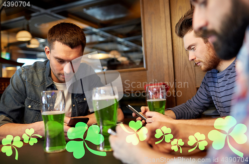 Image of friends with smarphones and green beer at pub