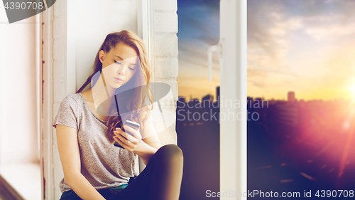 Image of sad pretty teenage girl with smartphone texting