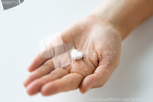 Image of close up of hand holding medicine heart pill