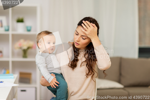 Image of tired mother with baby boy at home