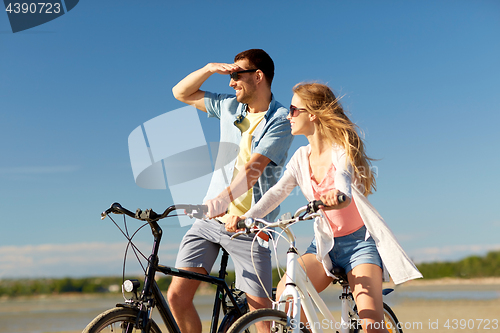 Image of happy young couple riding bicycles at seaside