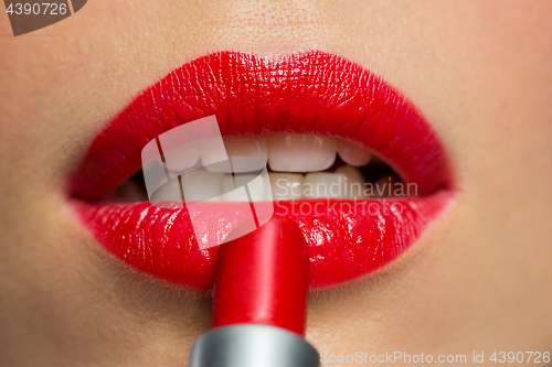 Image of close up of woman applying red lipstick to lips