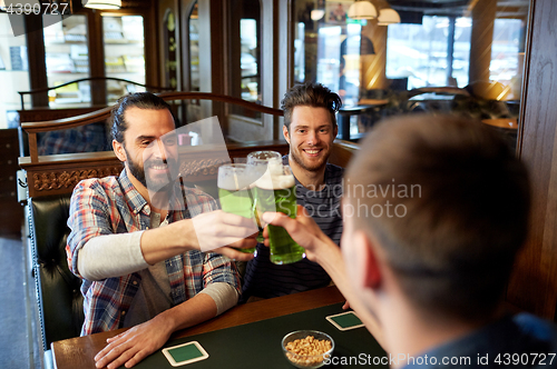 Image of male friends drinking green beer at bar or pub